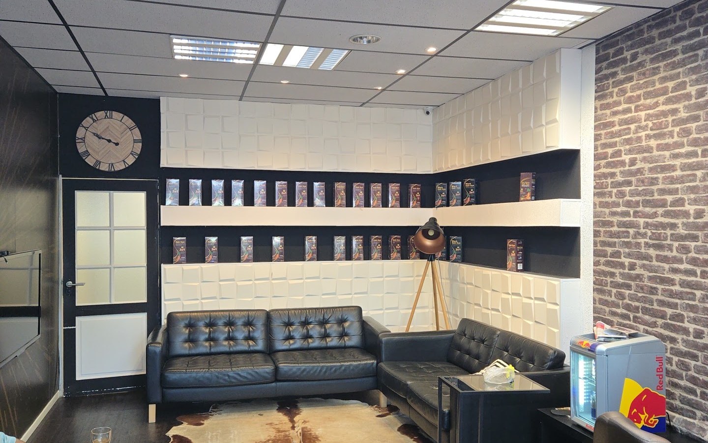 De wachthoek van Studio 54: een leren hoekbank, schappen met producten en een houten klok aan de muur